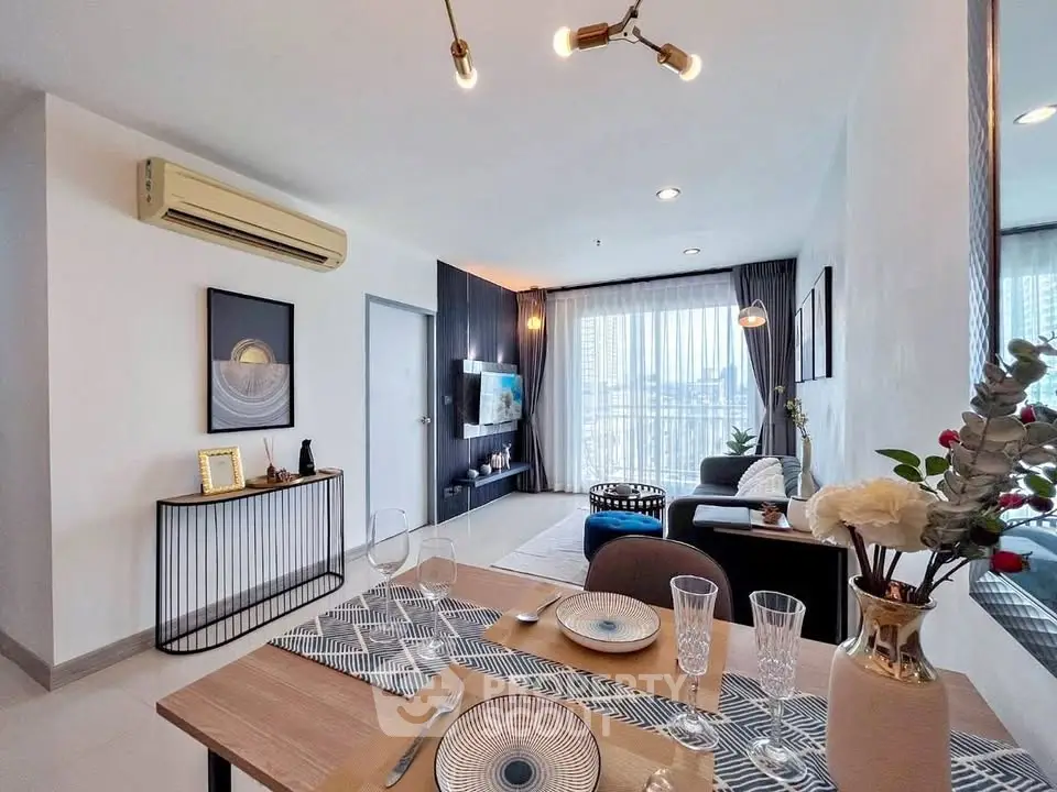 Modern living room with dining area, stylish decor, and large windows offering city views.