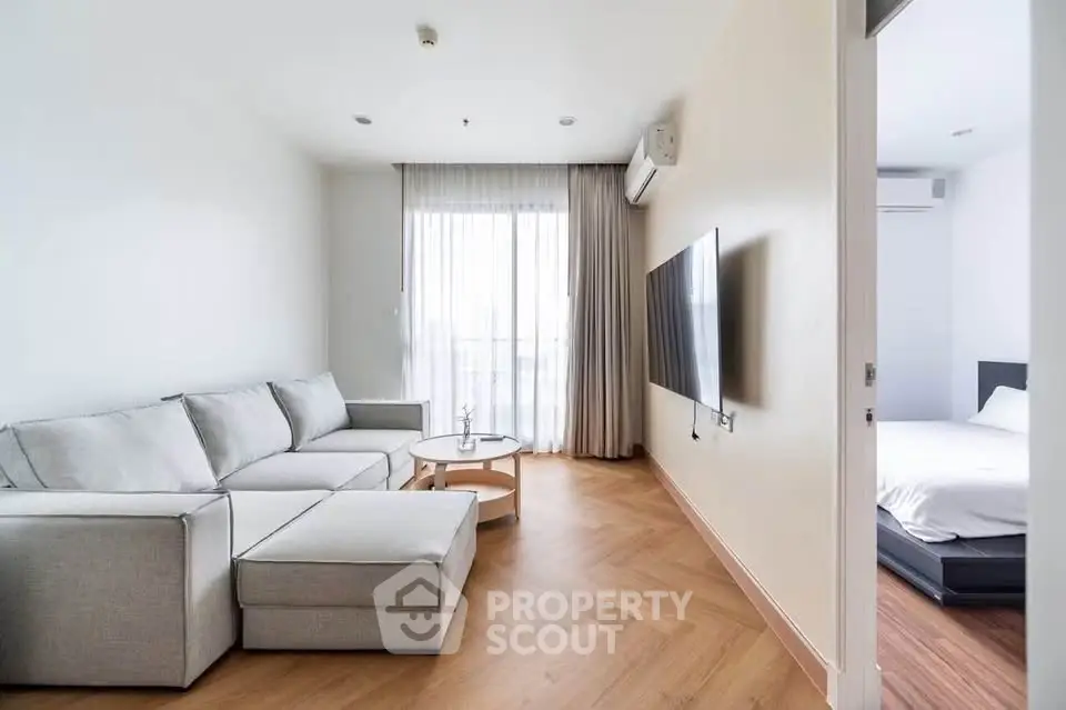 Modern living room with sleek design and natural light, featuring a cozy sectional sofa and wall-mounted TV.