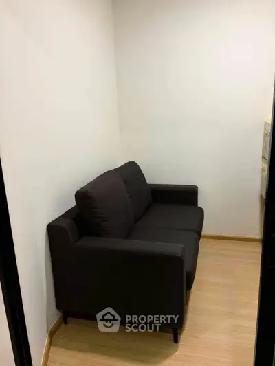 Cozy small room with a dark sofa and wooden flooring, perfect for a compact living space.