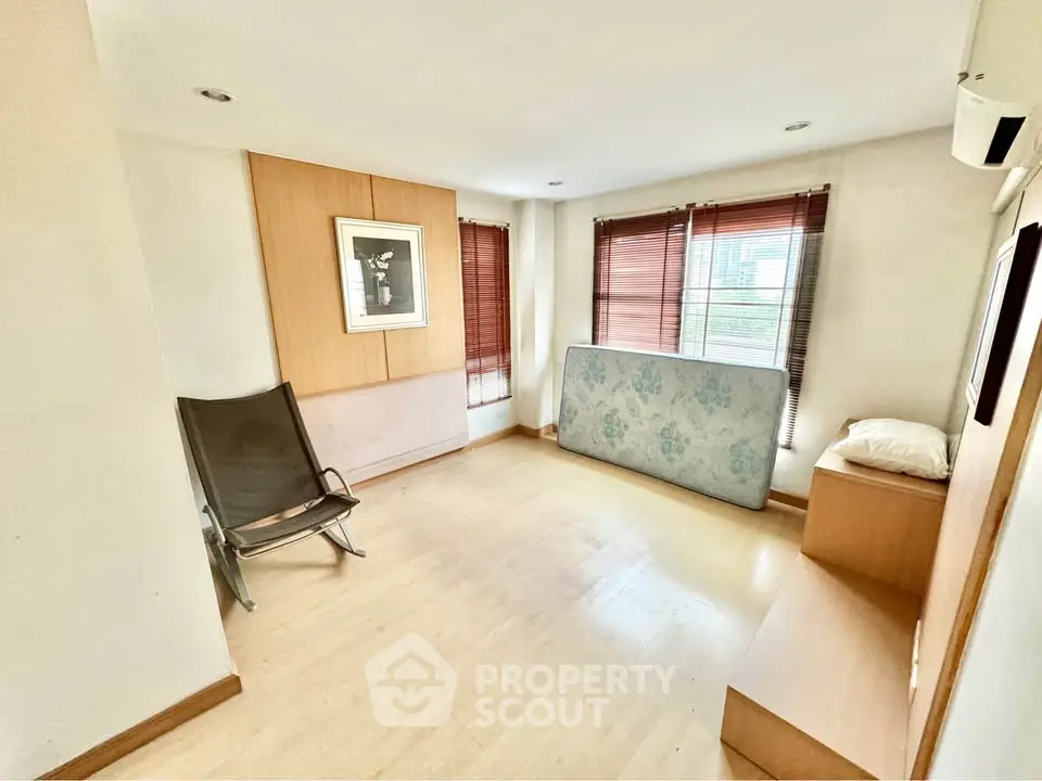 Spacious room with natural light, wooden flooring, and minimalist decor.