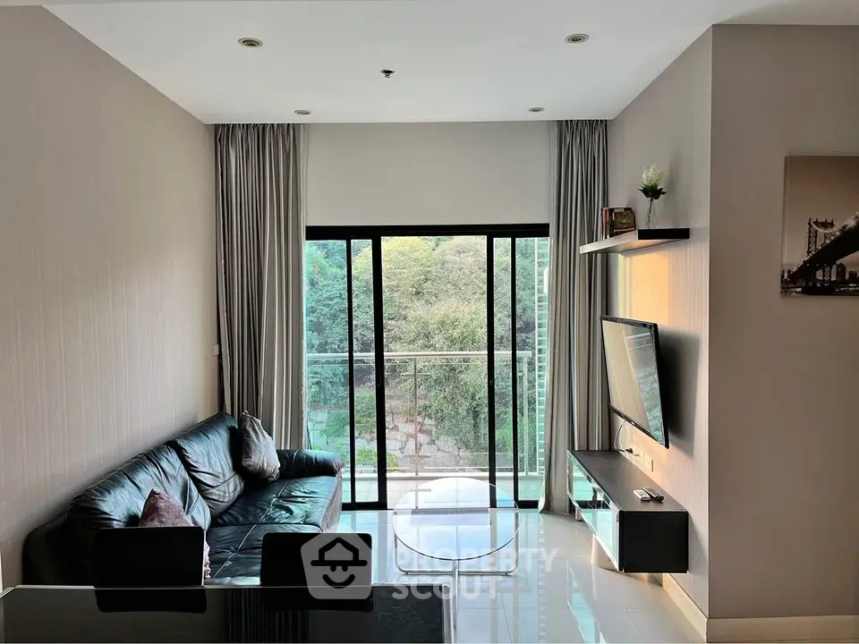 Modern living room with large window and balcony view, sleek furniture, and natural light.