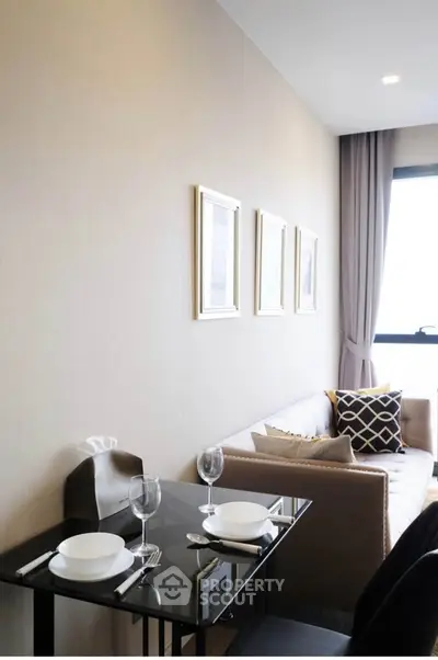 Modern living room with elegant dining setup and cozy sofa near large window.
