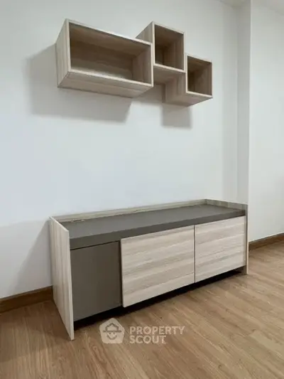 Modern minimalist living room with stylish wooden furniture and sleek wall-mounted shelves.