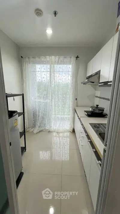 Modern kitchen with sleek white cabinets and large window for natural light