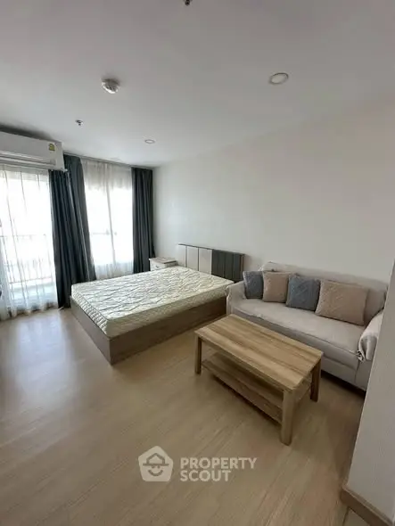 Modern bedroom with cozy sofa and natural light, perfect for relaxation.