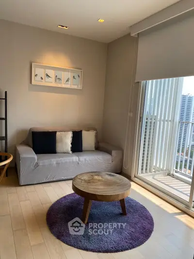 Modern living room with cozy sofa, round wooden table, and city view balcony.