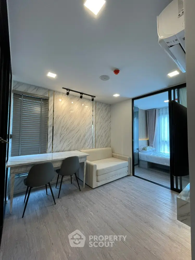 Modern living room with elegant decor and sliding glass doors leading to a cozy bedroom.