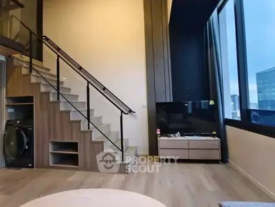 Modern duplex living room with staircase and large windows offering city views.