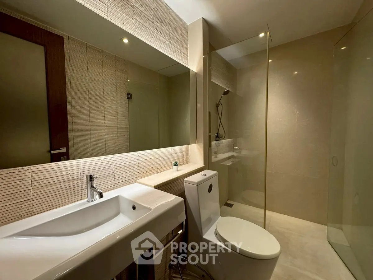 Modern bathroom with sleek design, featuring a glass shower and contemporary fixtures.
