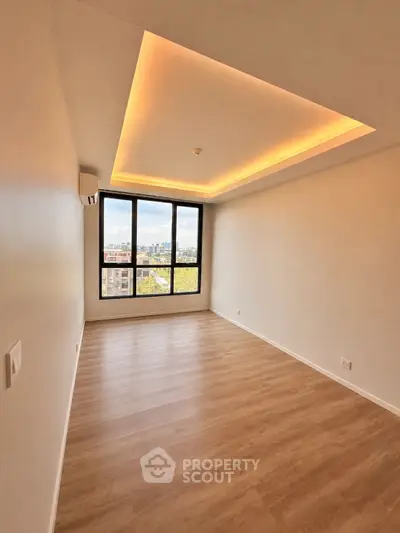 Spacious empty room with large window and wooden flooring, perfect for customization.