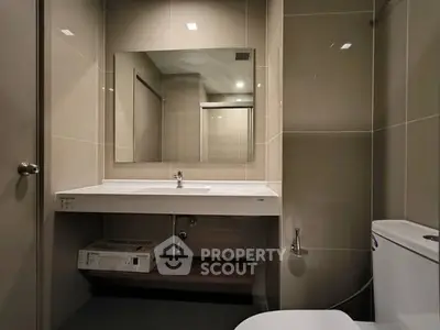 Modern bathroom with sleek fixtures and large mirror in contemporary apartment.