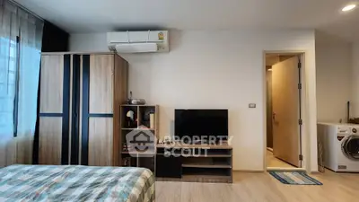 Modern bedroom with air conditioning, TV, and washing machine in a cozy apartment.