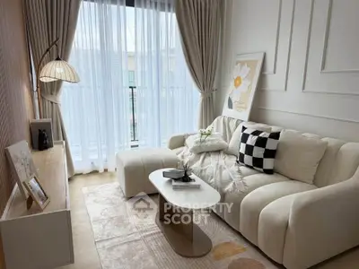 Elegant living room with modern decor, cozy sofa, and natural light through sheer curtains.