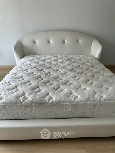 Luxurious bedroom with elegant white upholstered bed and plush mattress, perfect for restful nights.