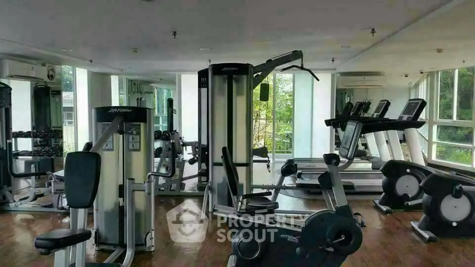Spacious gym with modern fitness equipment and large windows offering natural light and garden views.