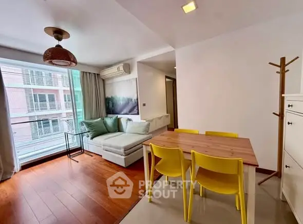 Modern living room with wooden flooring, cozy sofa, and dining area in a bright apartment.