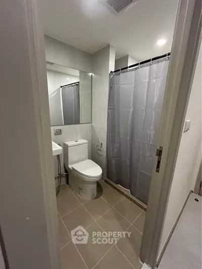 Modern bathroom with sleek design and neutral tones, featuring a shower curtain and contemporary fixtures.