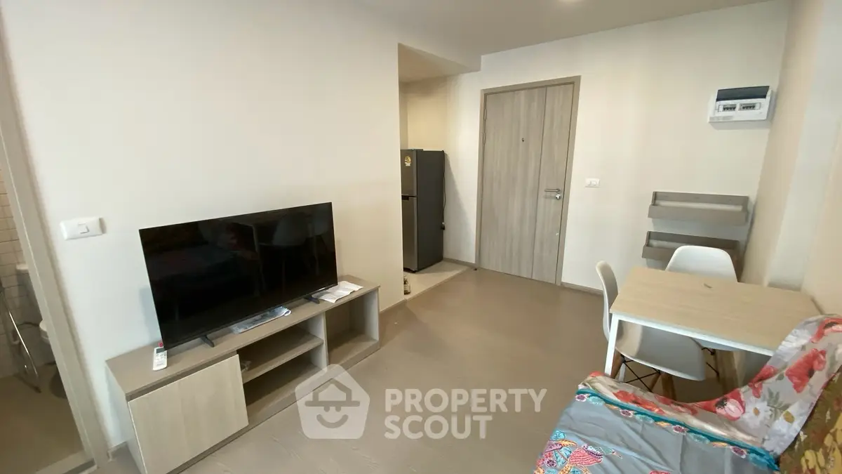 Modern living room with TV, dining table, and colorful sofa in a cozy apartment.