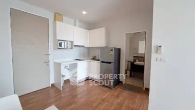 Modern kitchen with sleek white cabinets and stainless steel fridge in a cozy apartment.