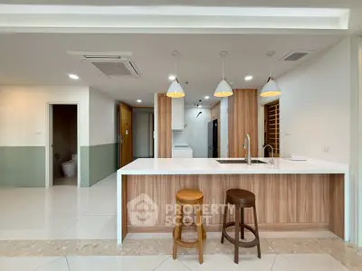 Modern kitchen with island, pendant lights, and wooden accents in a spacious apartment.