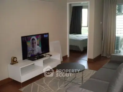 Cozy living room with modern TV setup and view into a bedroom, perfect for comfortable living.