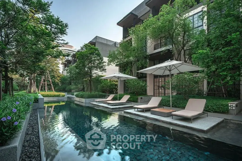 Luxurious residential pool area with sun loungers and lush greenery, perfect for relaxation and leisure.