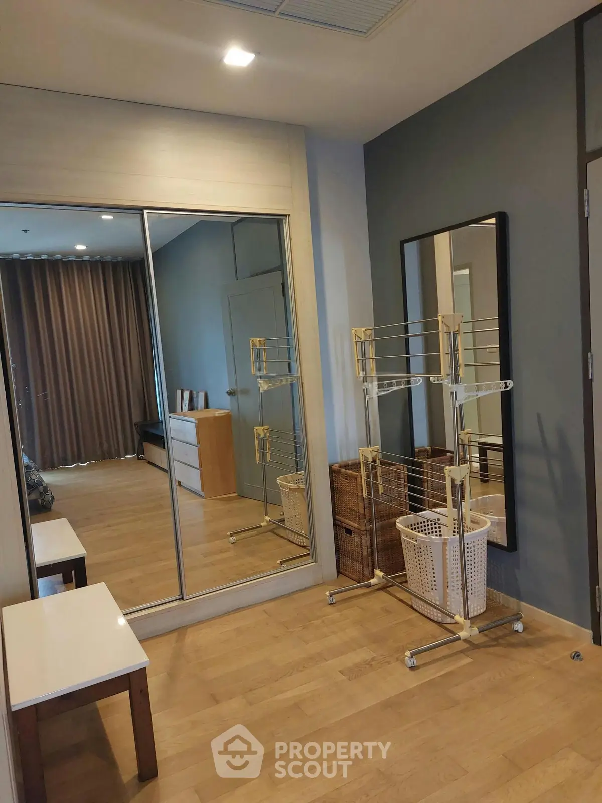 Spacious bedroom with mirrored wardrobe and wooden flooring in modern apartment.