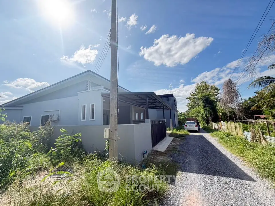 Charming suburban home with spacious driveway and lush greenery under a clear blue sky.
