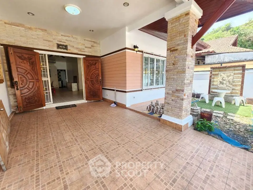 Charming home entrance with elegant wooden doors and cozy outdoor seating area.