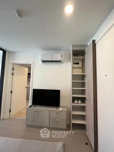 Modern living room with TV, air conditioning, and open closet in a stylish apartment.