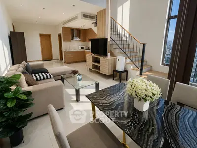 Luxurious modern living room with open kitchen and stylish staircase in high-rise apartment.