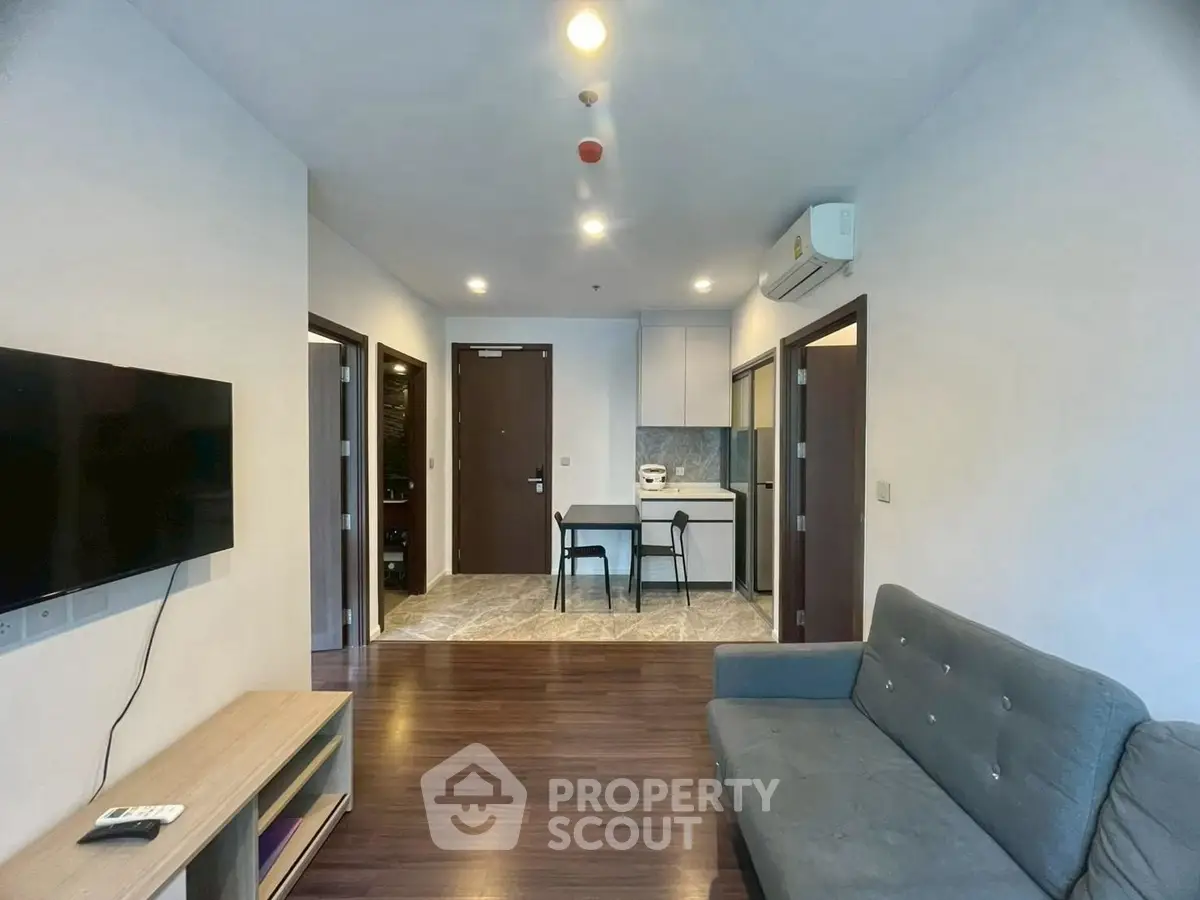 Modern living room with sleek furniture and open kitchen layout in a stylish apartment.