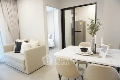 Modern apartment interior with cozy living area and sleek dining space, featuring a stylish kitchen with stainless steel fridge.