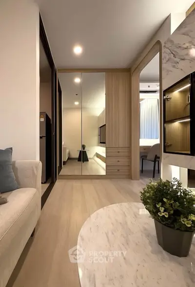 Modern living room with elegant decor and mirrored wardrobe, featuring a cozy sofa and stylish table.