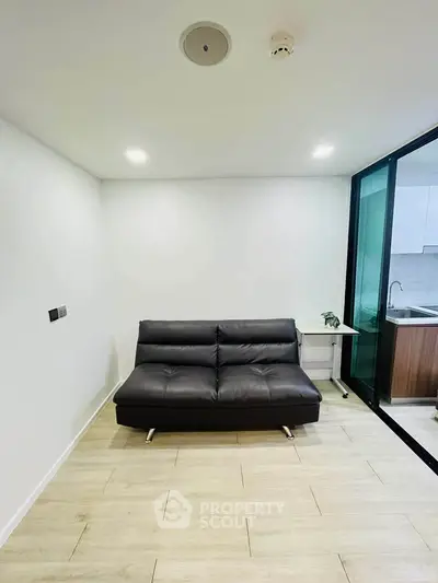 Modern living room with sleek black sofa and open kitchen layout