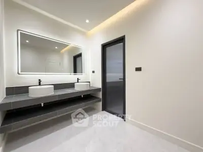 Modern bathroom with dual sinks and large illuminated mirror