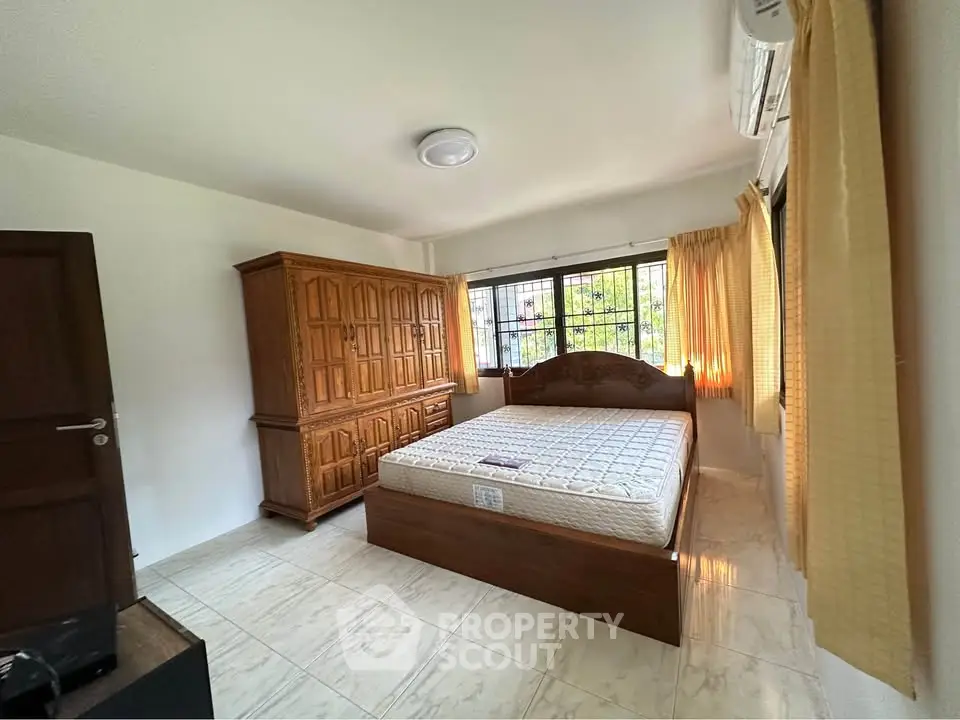 Spacious bedroom with wooden furniture and large windows for natural light