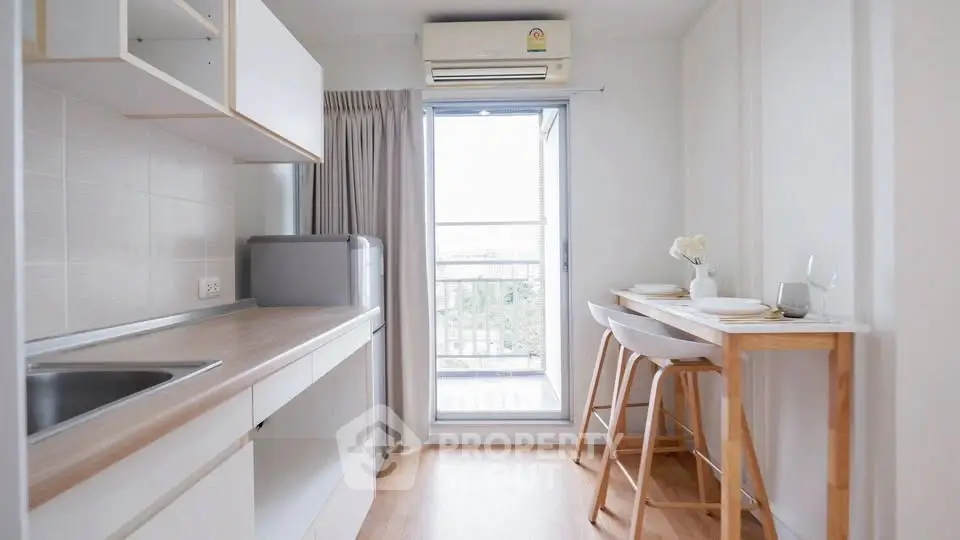 Chic modern kitchen with balcony view, featuring sleek countertops and cozy dining area.