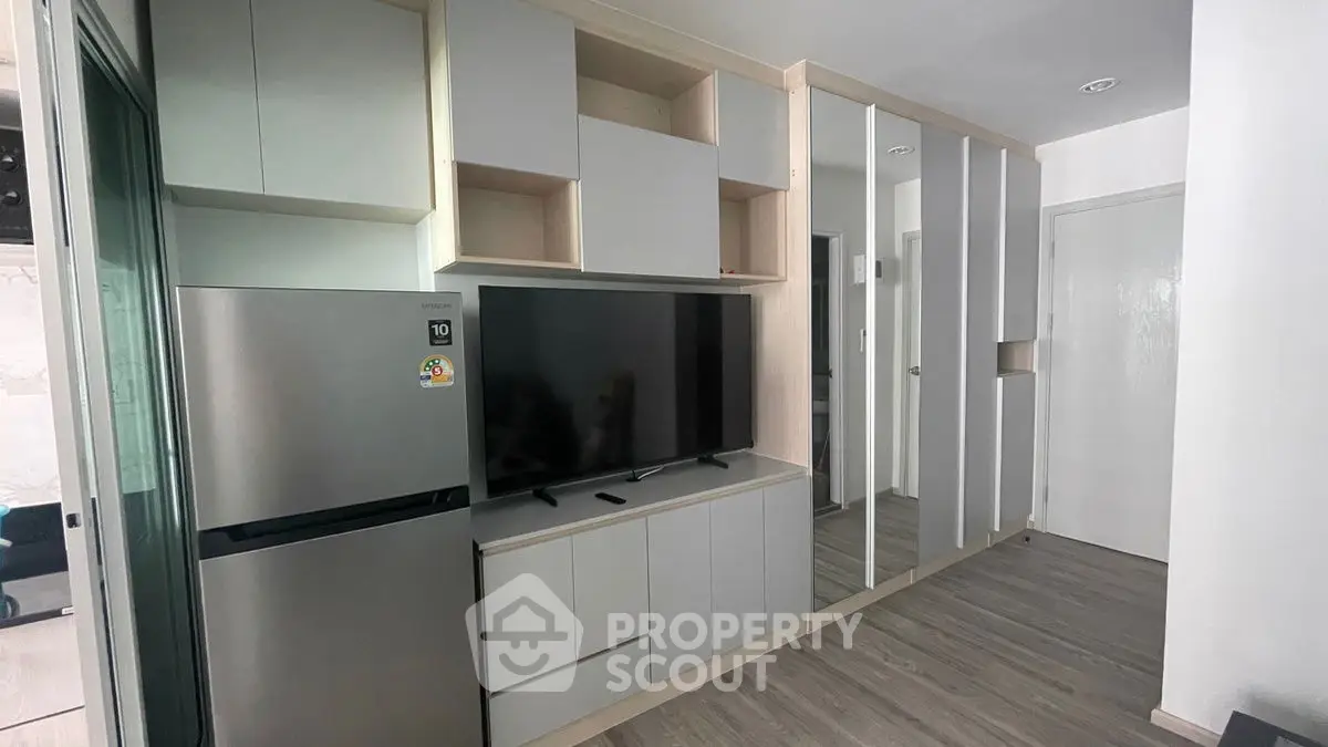 Modern living room with sleek cabinetry and stainless steel fridge