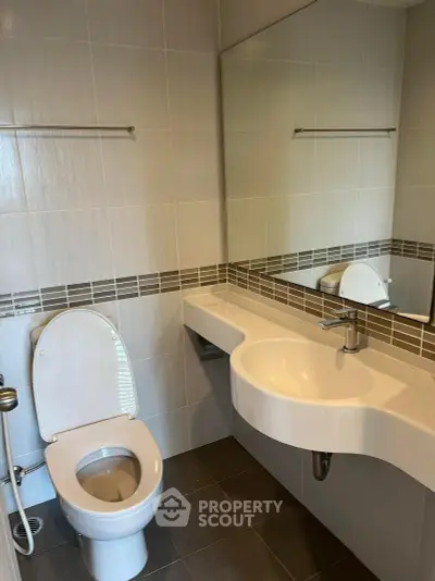Modern bathroom with sleek fixtures and large mirror in a contemporary home.