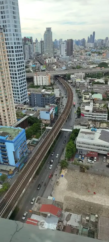 Stunning cityscape view from high-rise building showcasing urban skyline and railway tracks.