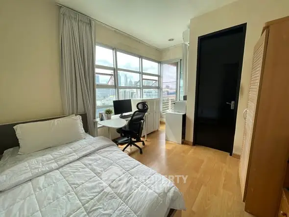 Bright bedroom with city view, featuring a cozy bed and modern workspace.