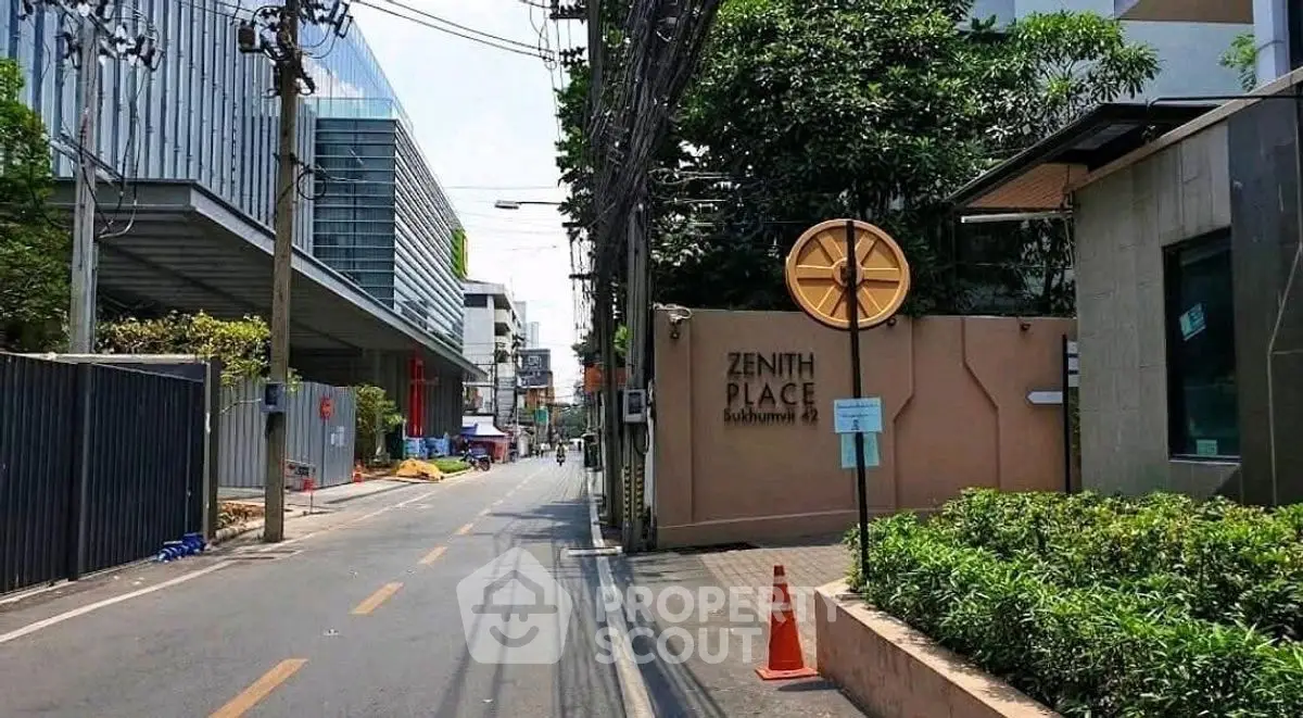 Street view of modern building with lush greenery and clear blue sky