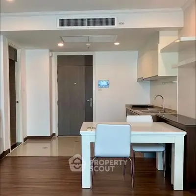Modern apartment interior with open kitchen and dining area, featuring sleek design and wooden flooring.