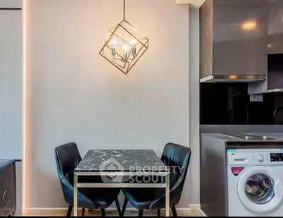 Modern dining area with stylish lighting and integrated washing machine in sleek kitchen.