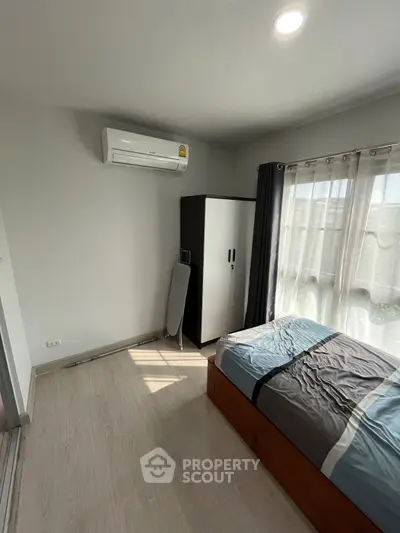 Cozy bedroom with natural light, air conditioning, and modern furnishings for comfortable living.