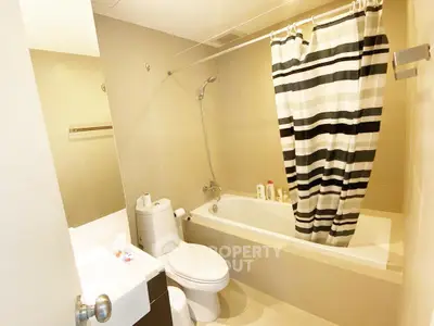 Modern bathroom with bathtub and striped shower curtain in a cozy apartment.