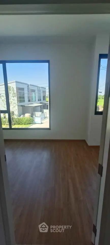 Bright empty room with large windows and wooden flooring in modern home