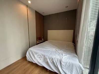 Cozy modern bedroom with wooden flooring and large window for natural light