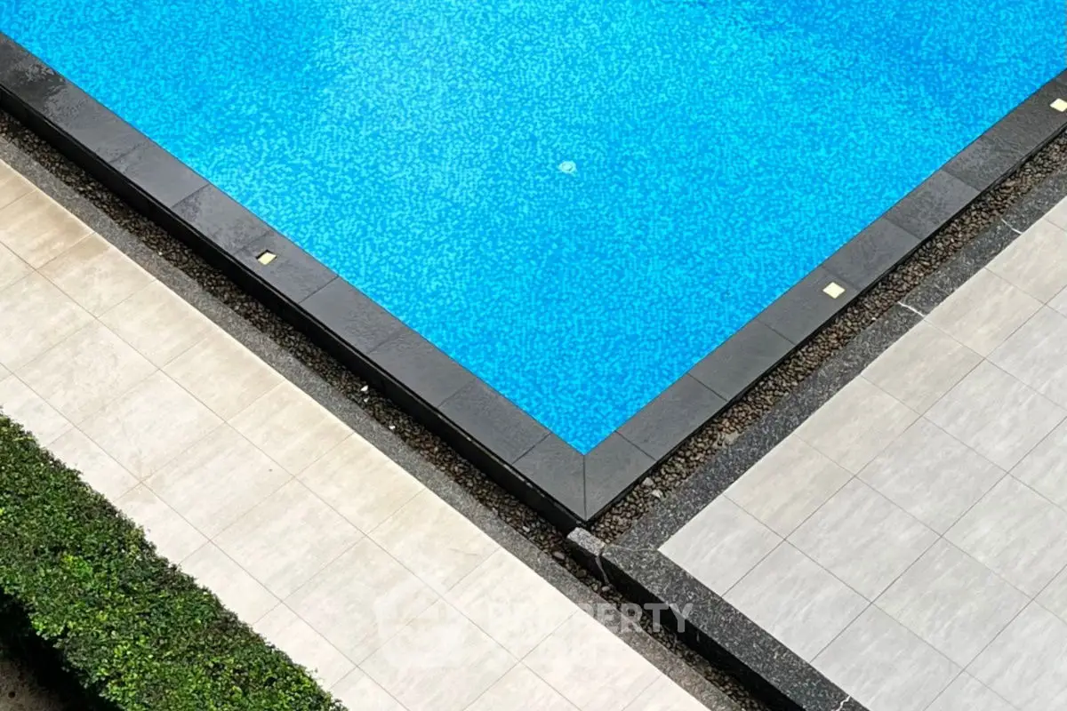 Luxurious outdoor pool with elegant tile surround and lush greenery